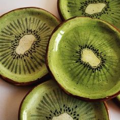 four pieces of kiwi sitting on top of each other in green bowls with black spots