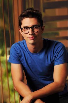 a young man wearing glasses sitting down