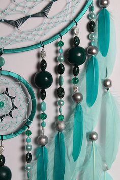 a dream catcher with beads and feathers hanging from it's side on a wall