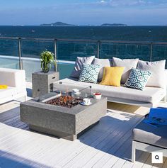 an outdoor fire pit on a deck overlooking the ocean