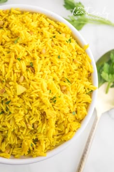 a white bowl filled with yellow rice and garnished with parsley on the side