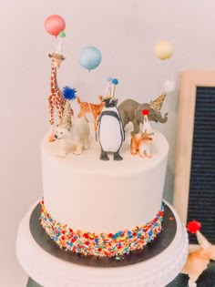 a birthday cake decorated with animals and balloons