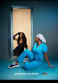 two women sitting on the ground in front of a mirror