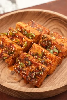 several pieces of tofu on a wooden plate with sesame seeds and seasoning sprinkles