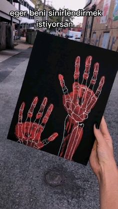 a person holding up a piece of art that looks like hand prints on black paper