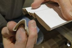 a person is making something out of paper and glues it with their hands on top of another piece of cardboard