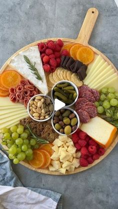 a platter filled with cheese, crackers, nuts and fruit on top of a table