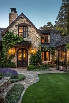 a stone house with lots of greenery on the front and side walls, surrounded by lush green grass