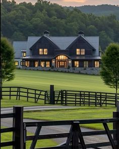 a large house sitting in the middle of a lush green field next to a forest