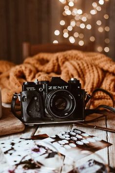 a camera sitting on top of a wooden table next to a candle and some pictures