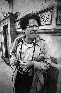 black and white photograph of an older woman with glasses standing in front of a building