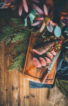 raw meat on a cutting board surrounded by fresh herbs