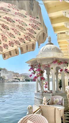 an outdoor gazebo with flowers on it next to the water