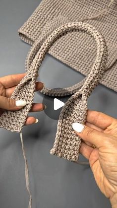 two hands are holding scissors on top of a piece of knitted material that is being held by another hand