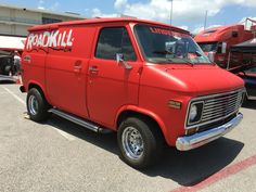 a red truck parked in a parking lot next to other trucks