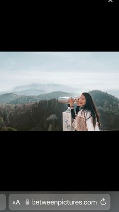 a woman standing on top of a mountain holding a camera