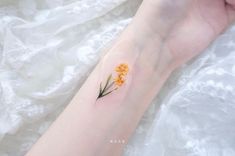 a small yellow flower tattoo on the wrist