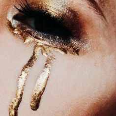 a woman's eye with gold glitter on her lashes and the bottom part of her face