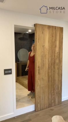 a woman standing in front of a wooden door with her reflection in the mirror behind it