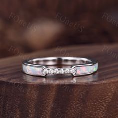 an opal and diamond ring on top of a wooden table