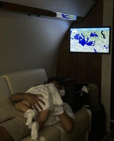 a person laying on a couch in front of a tv with a map on the wall