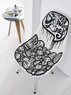 a white chair with black and white graffiti on it's back, next to a table