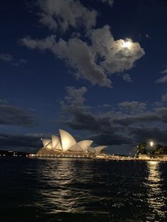 the sydney opera house is lit up at night, as seen from across the water