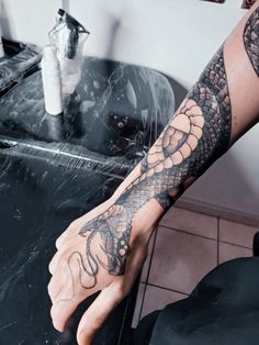 a person with a tattoo on their arm and hand is sitting in front of a table