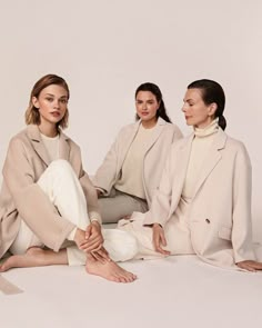 three women sitting on the ground with their legs crossed and one woman in white pants