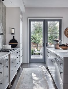 a kitchen with white cabinets and an open glass door that leads to the outside patio