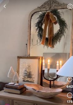 a christmas wreath is hanging on the wall above a table with candles and other decorations