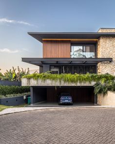 a car is parked in front of a modern house with plants growing on the roof