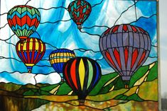 there are many hot air balloons in the sky on this stained glass window pane