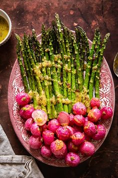 asparagus and radishes on a plate with dipping sauce