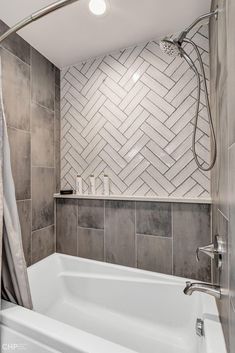 a white bath tub sitting next to a shower in a bathroom under a tiled wall