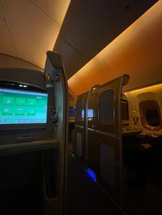 the inside of an airplane with many seats and televisions on each side of the aisle