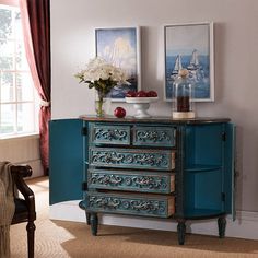 a blue dresser with flowers and pictures on the wall