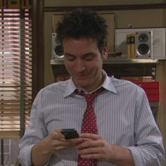 a man in a tie looking at his cell phone while wearing a shirt and tie