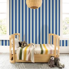 a small child's bed in front of a blue striped wall