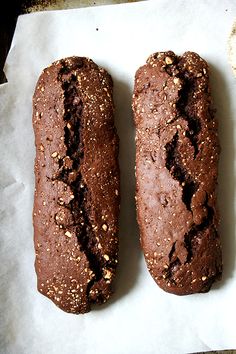 two brown breads sitting on top of a piece of paper next to each other