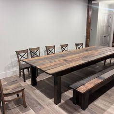 a dining room table with six chairs and a bench in front of the table is made out of wood planks