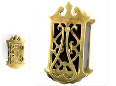 a gold brooch with an ornate design on the front and back of it, next to another brooch