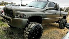 a silver truck parked in a field next to other cars and trucks on the grass