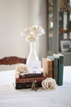 there is a vase with flowers and books on the table next to eachother