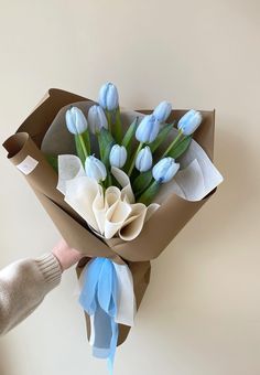 a bouquet of blue tulips in a brown paper wrapper with someone holding it