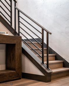 there is a book shelf under the stairs next to the bannister on the floor