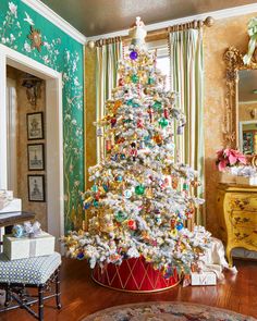 a decorated christmas tree in the corner of a room with green walls and floral wallpaper