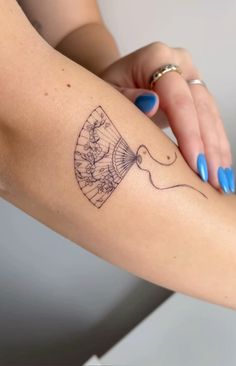 a woman's arm with a tattoo that has a fan and flowers on it