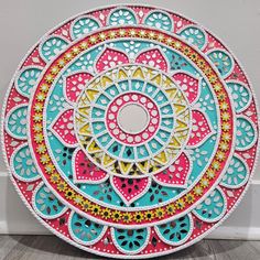 a colorful paper plate sitting on top of a wooden floor next to a white wall