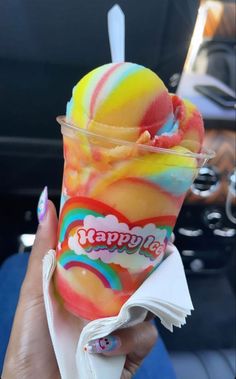 a person holding up an ice cream sundae with rainbow swirls on it's wrapper